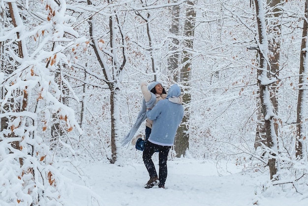 Um homem gira uma mulher em seus braços na floresta de inverno