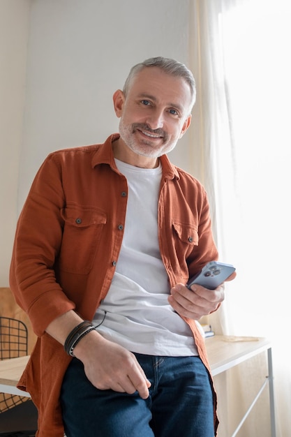 Um homem grisalho na camisa laranja parecendo feliz