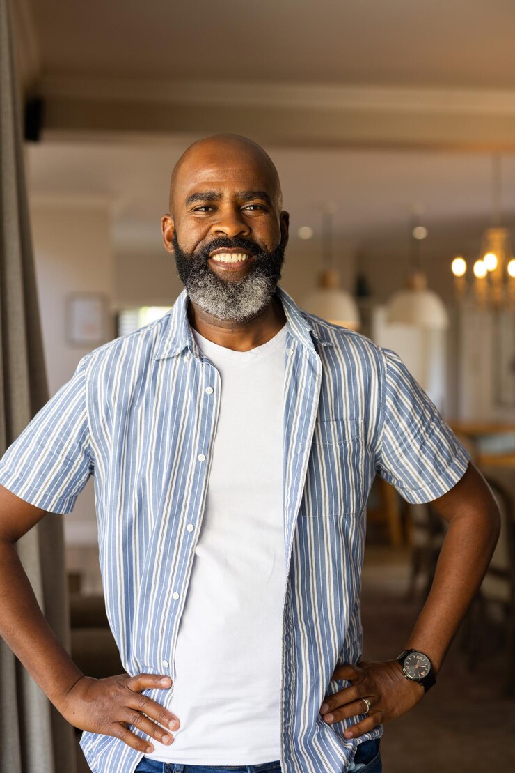 Foto um homem idoso afro-americano sorridente de pé com confiança com as mãos nos quadris em uma casa moderna