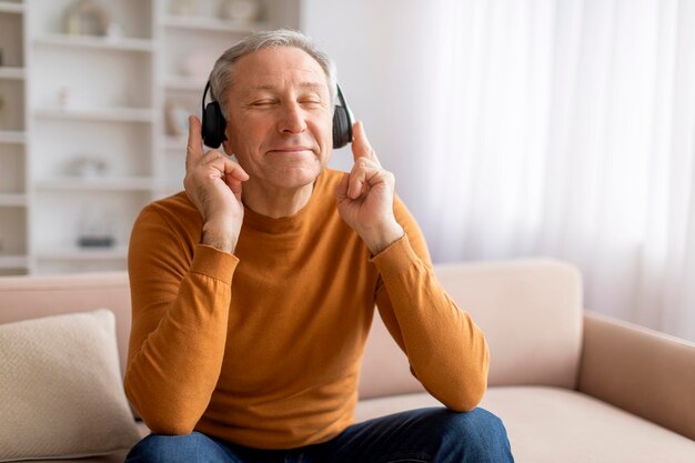 Um homem idoso alegre a desfrutar de boa música em casa.