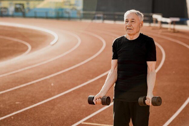 Um homem idoso com halteres em uma pista