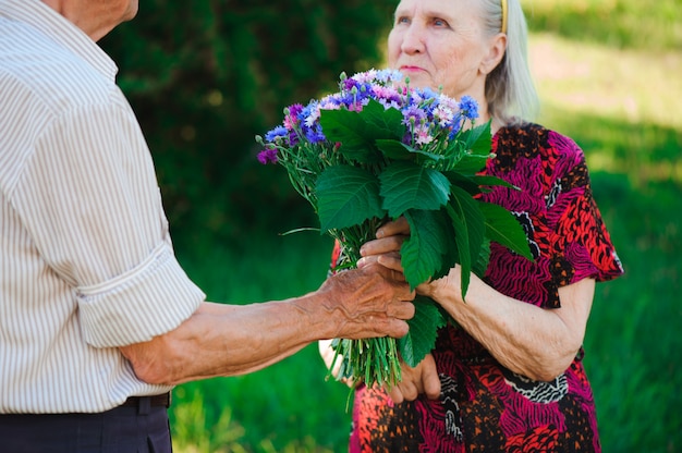 Um homem idoso de 80 anos dá flores para sua esposa