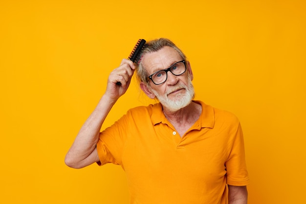 Um homem idoso em uma camiseta amarela com um pente de cabelo grisalho