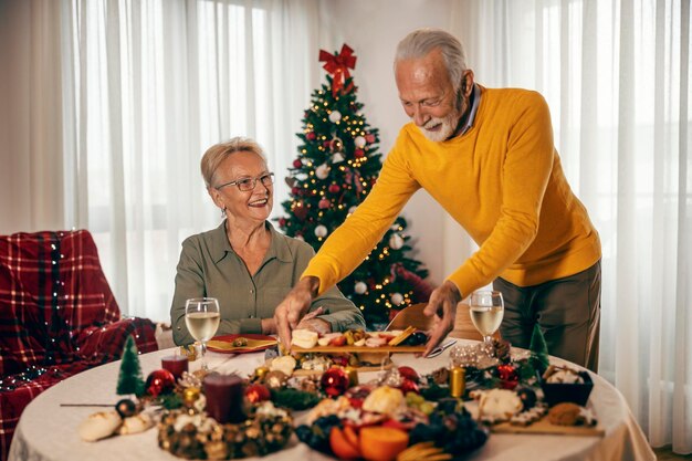 Foto um homem idoso está trazendo comida para uma mesa de natal em casa no natal e no ano novo
