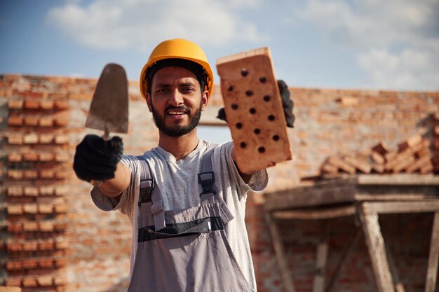 Foto um homem indiano alegre e bonito está no canteiro de obras.