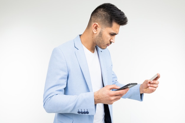 Um homem insere dados com cartão de crédito em um telefone celular para fazer uma compra via Internet em um branco