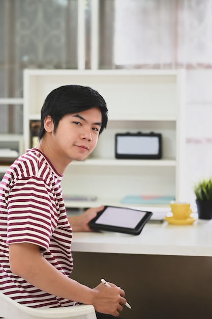 Um homem inteligente está trabalhando com um tablet computador enquanto está sentado e voltando para a mesa de trabalho