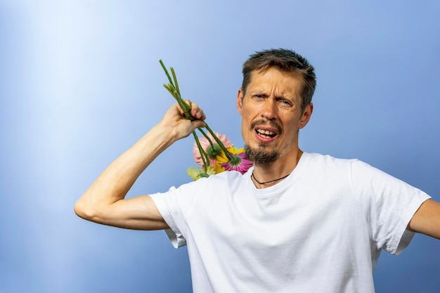 Um homem irritado com raiva em uma camiseta branca sacode e balança flores