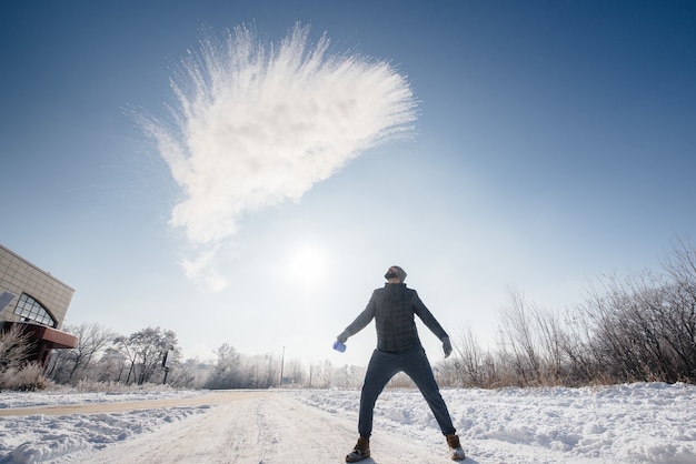 Um homem joga água fervente no frio, que instantaneamente se transforma em vapor. O truque da água quente.