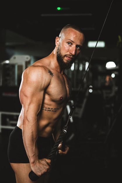Foto um homem jovem fisiculturista muscular fazendo treinamento duro para os músculos dos braços no ginásio.