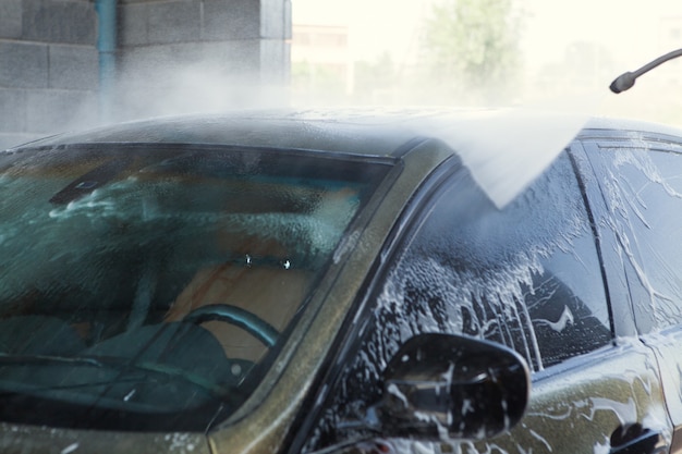 Um homem lava seu carro com água