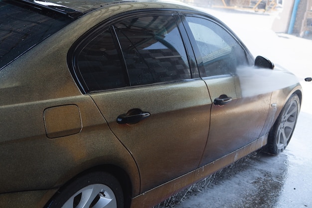 Um homem lava seu carro com água