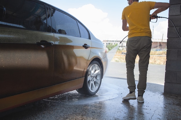 Um homem lava seu carro com água