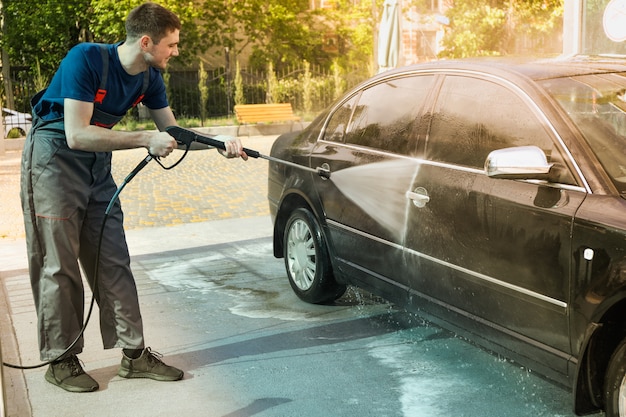 Um homem lava um carro em uma lavagem manual.