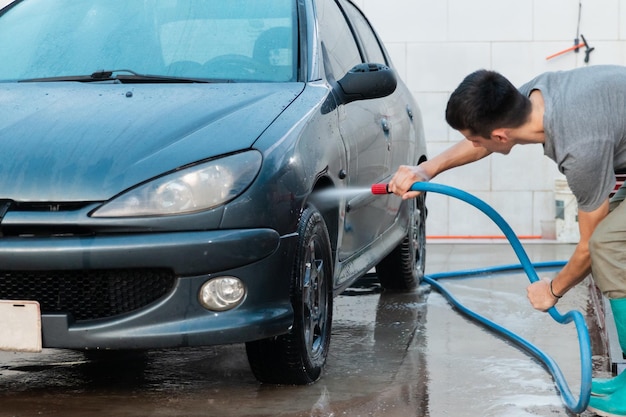 Um homem lavando o para-lama dianteiro de um carro