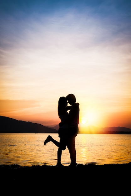 Foto um homem levantando um fundo de mulher é lago montanha e pôr do sol