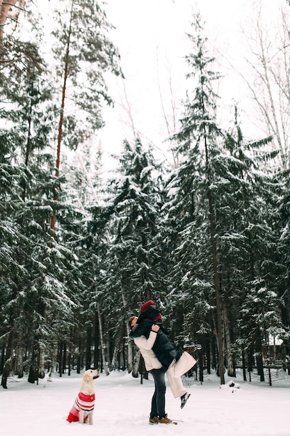 Um homem levantou uma mulher nos braços no meio de uma floresta nevada