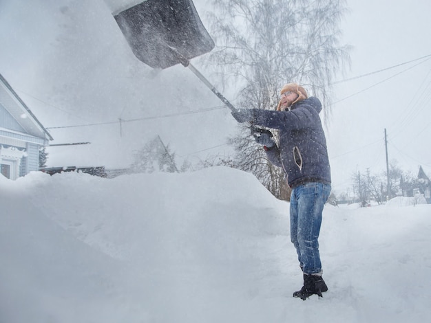 um homem limpa a estrada da neve com uma pá neve na manhã de inverno