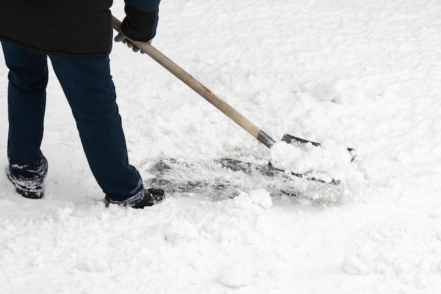 Um homem limpando a neve recém-caída com uma pá de ferro confiável completa com um punho de madeira