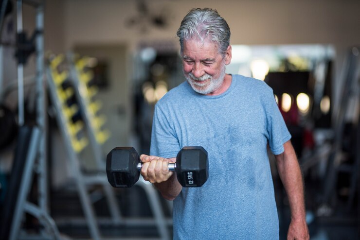 Foto um homem maduro segurando um peso na academia fazendo exercícios para ser saudável e fitness - sênior em uma academia fazendo atividade segurando um haltere