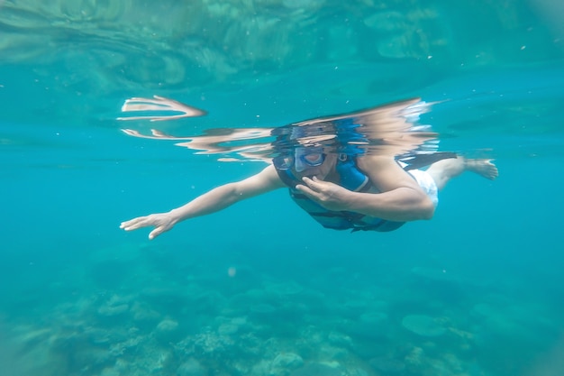 Um homem mergulhando de snorkel em um recife de coral em uma praia