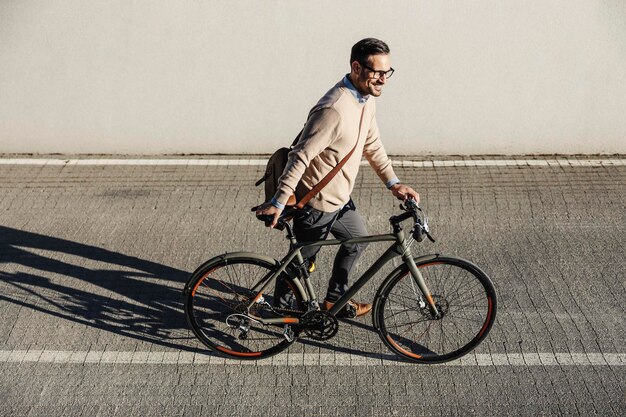 Um homem moderno empurrando bicicleta na rua em dia ensolarado