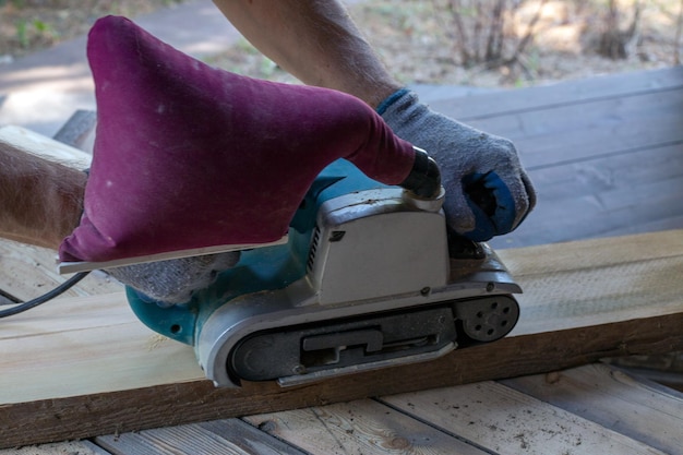 Um homem mói tábuas de madeira com um moedor Passatempo de carpintaria Woodwork