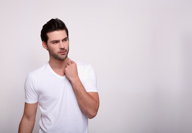 Um homem moreno jovem e bonito posa em um branco.