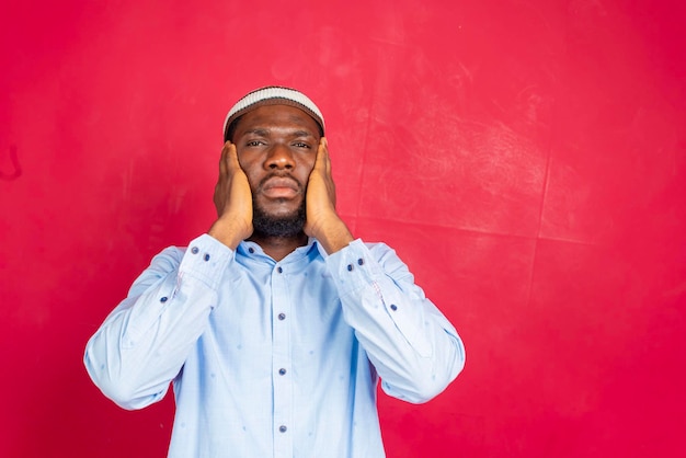 Um homem muçulmano africano fazendo uma oração tradicional a Deus enquanto usa um tradicional chapéu Dishdasha