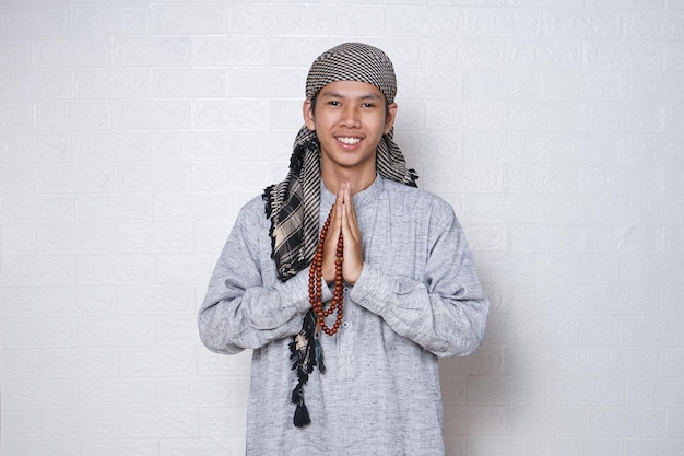 Um homem muçulmano, sorrindo usando um turbante na cabeça e segurando contas de oração.