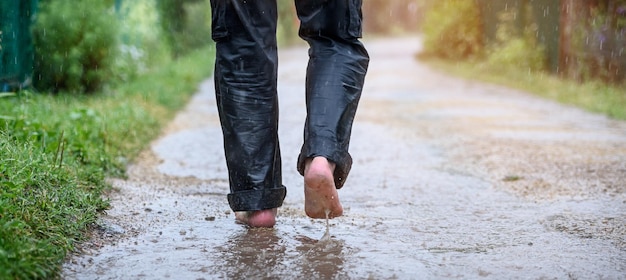 Um homem na chuva está descalço em poças