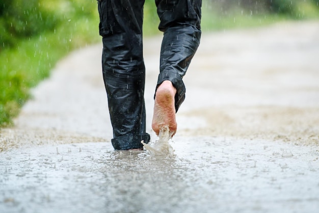 Um homem na chuva está descalço em poças