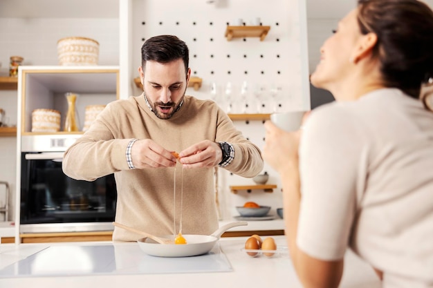 Um homem na cozinha preparando ovos fritos para sua esposa em sua casa aconchegante