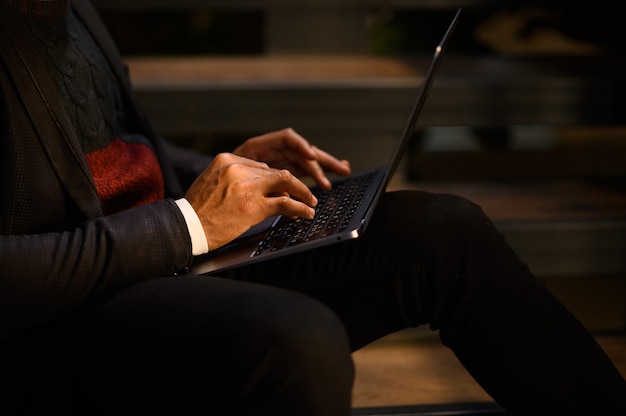 Um homem negro trabalha em um laptop, close-up de suas videoconferências