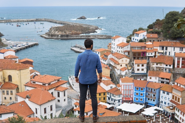 Um homem observando as casas de uma cidade costeira de cima