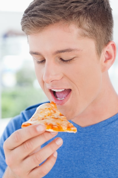 Um homem olhando uma fatia de pizza na frente dele enquanto ele está prestes a comer