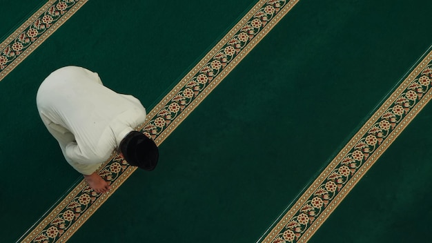 Um homem orando em um tapete de oração em um templo.