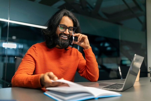 Um homem oriental alegre a organizar uma reunião de negócios a falar ao telefone.