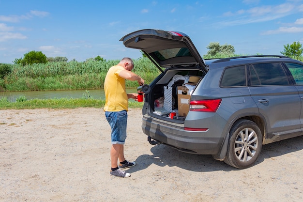 Um homem parado ao lado de um carro.