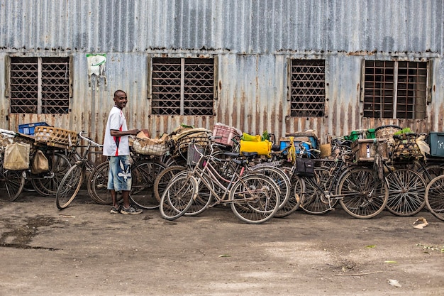 Um homem parado em frente a um prédio com bicicletas em Zanzibar, Tanzânia