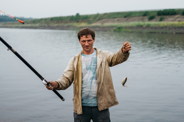 Um homem pegou um peixe. Pescador pegou um peixe pequeno