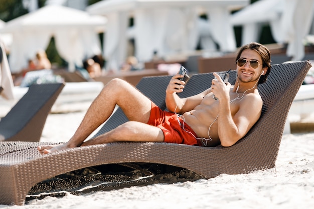 Um homem posando e ouvindo música na praia