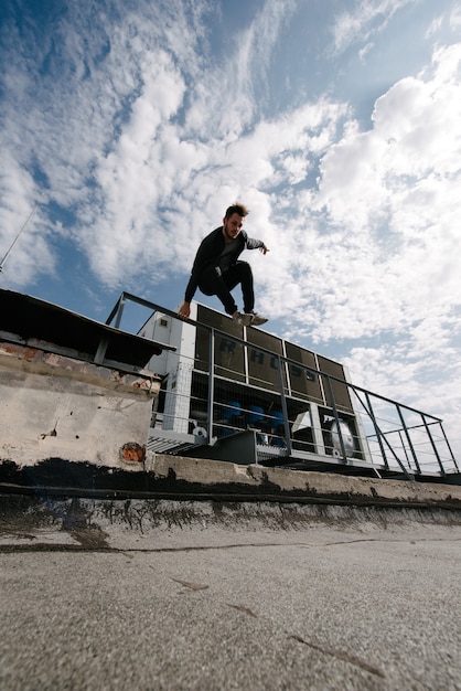 Um homem pratica parkour, corre e pula obstáculos