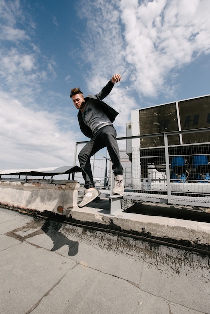 Um homem pratica parkour, corre e pula obstáculos