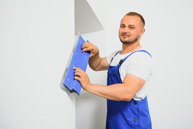 Um homem processa a parede com uma espátula. Estucador no trabalho.