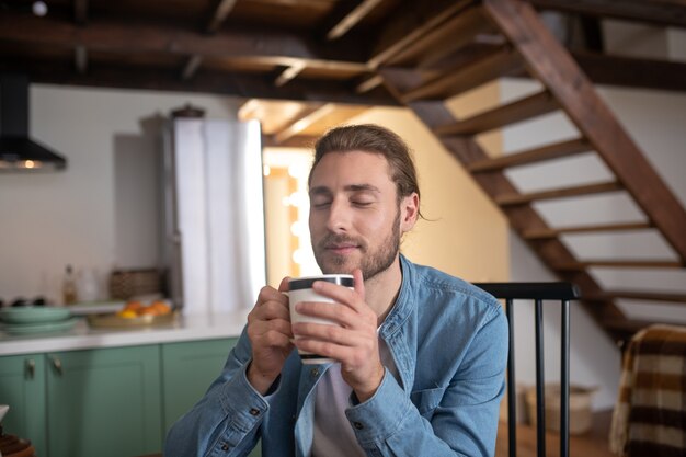 Um homem relaxado tomando seu chá de ervas favorito