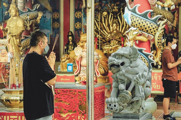 Um homem reza em frente a um templo com uma placa que diz 'a palavra chinesa'.