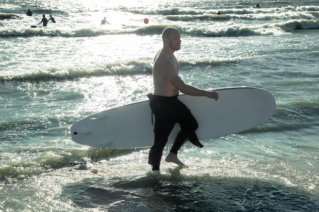 um homem sai do mar com uma prancha de surf