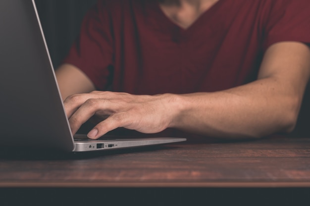 Um homem segura e usa um notebook