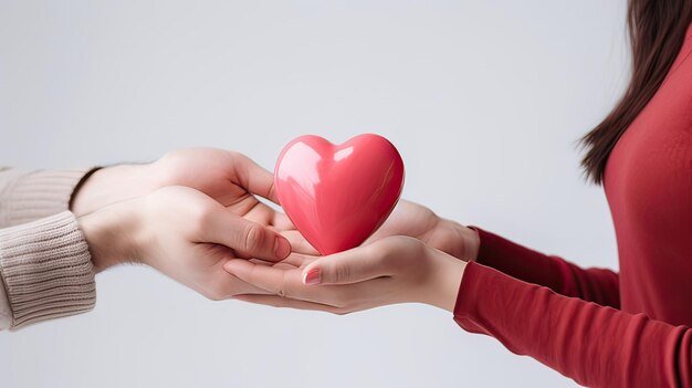 um homem segura em suas mãos um modelo de um coração vermelho em um fundo rosa o conceito de amor